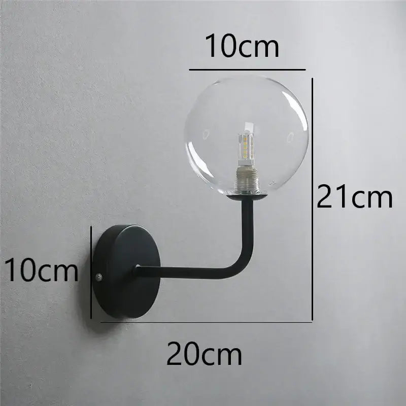 Black metal wall lamp with a clear glass ball housing an led bulb featured in decorbites glass ball collection
