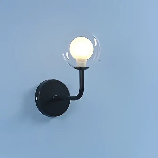 Black wall lamp with curved arm and clear glass ball featuring illuminated bulb for bedroom decorbites glass ball design
