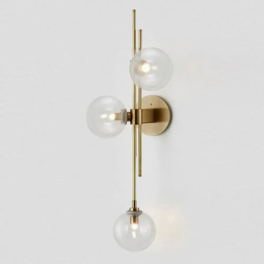 Retro brass wall sconce with three clear glass globe bulbs arranged vertically for dining room lighting