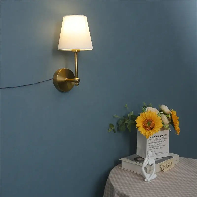 Gold led retro wall lamp featuring a gold-toned brass sconce with a white fabric shade for bedroom use