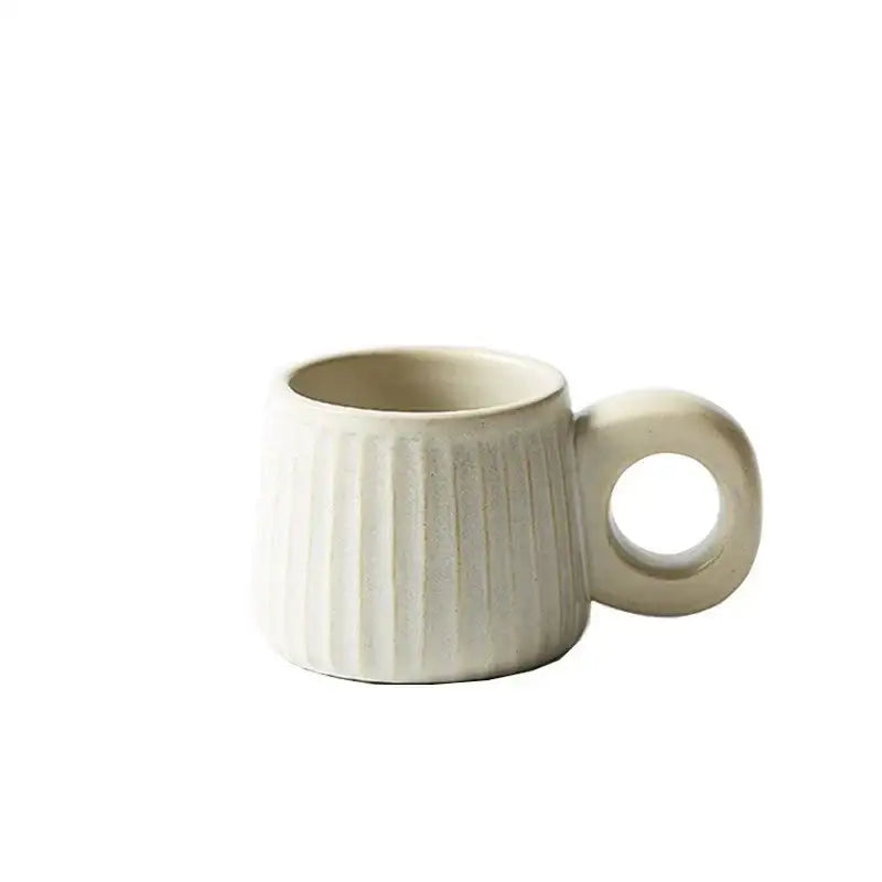 Cream-colored handmade nordic ceramic mug with vertical ridges and circular ring handle for kitchen coffee use