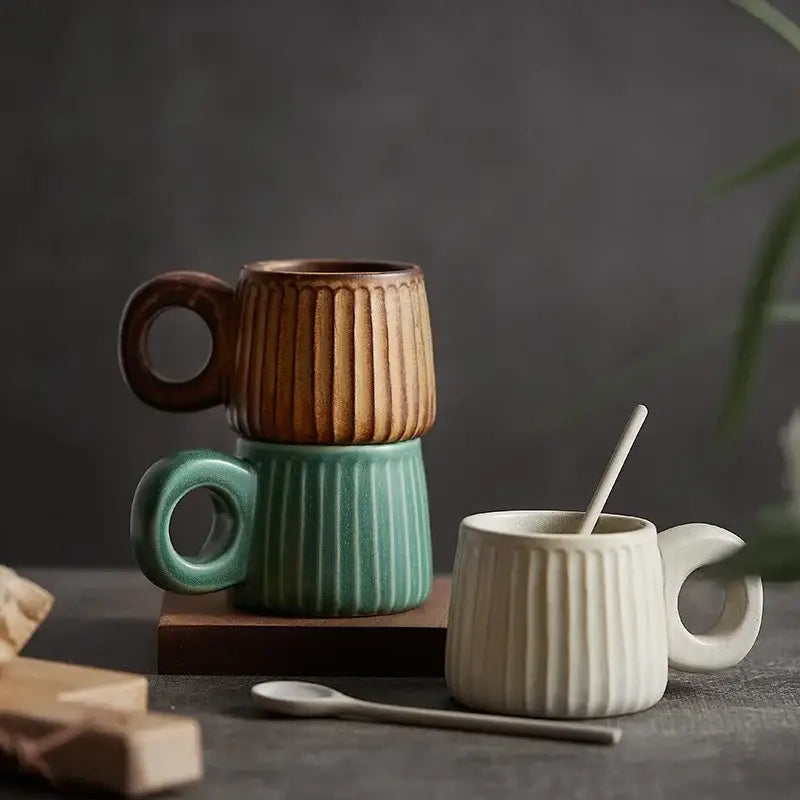 Three handmade nordic ceramic mugs with vertical ribs and ring handles in brown teal and off-white by decorbites