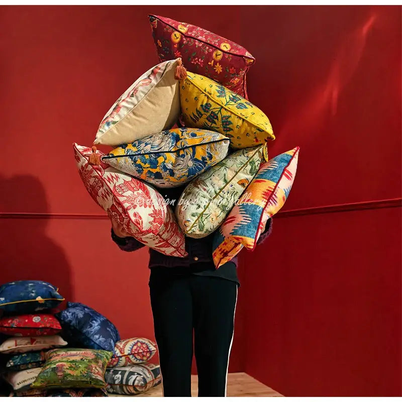 A person holds a vibrant stack of decorbites circus retro pillow covers with floral geometric patterns and tassels