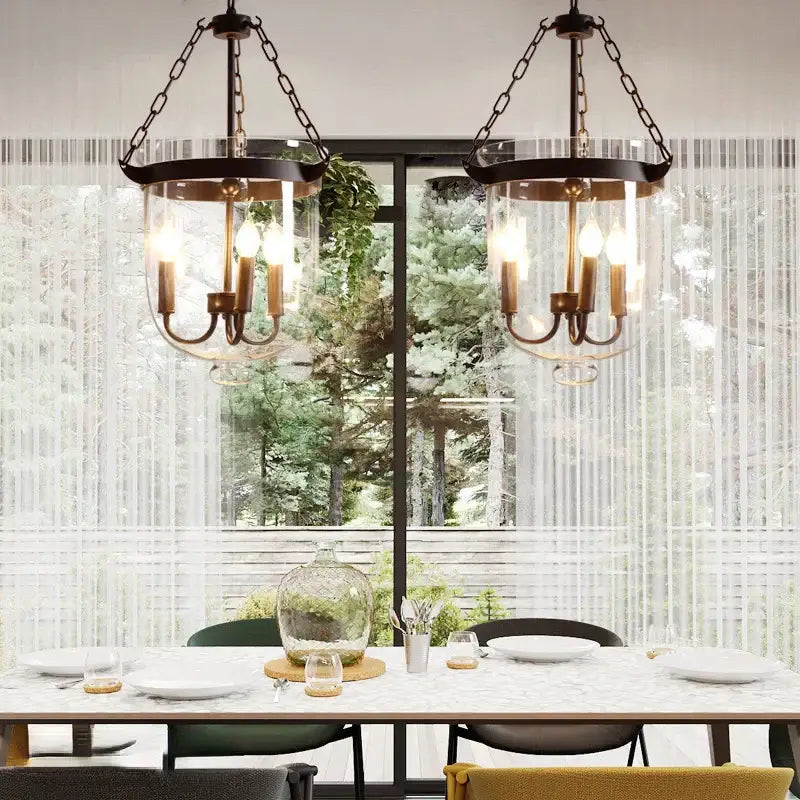 Two black wrought iron retro dark bronze decorbites glass bucket pendant lights with clear glass shades hang above dining table