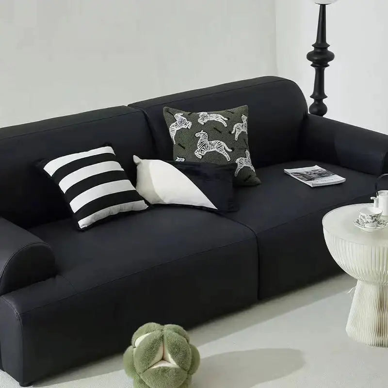 Black upholstered sofa with plush cushions and retro dark green zebra embroidered jacquard luxury pillow covers