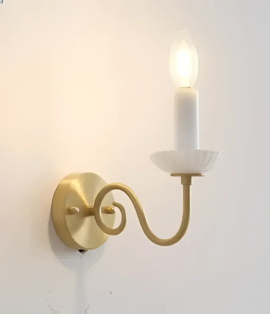 Gold-toned wall sconce with curved ornate arm and white ceramic candle holder for decorbites cream white led lighting