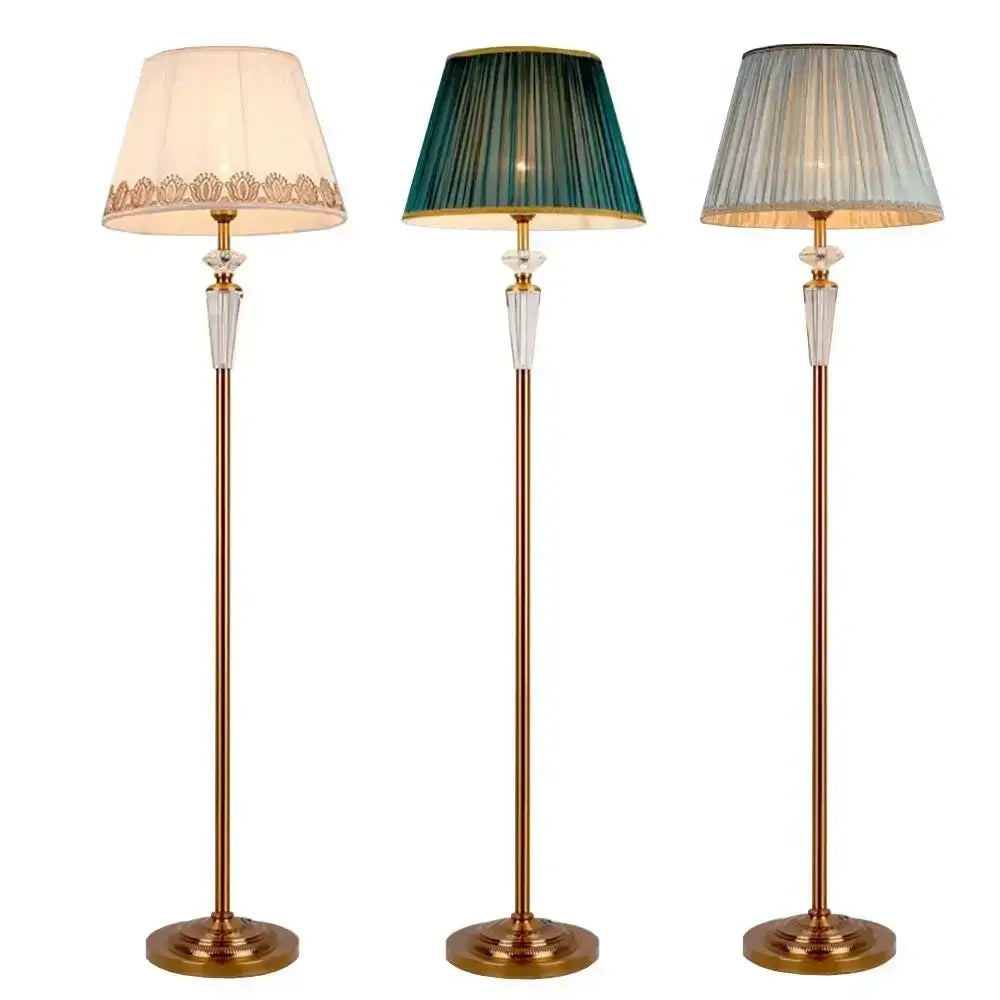Three elegant brass crystal floor lamps with cream lace edged, deep green pleated, and light gray textured shades