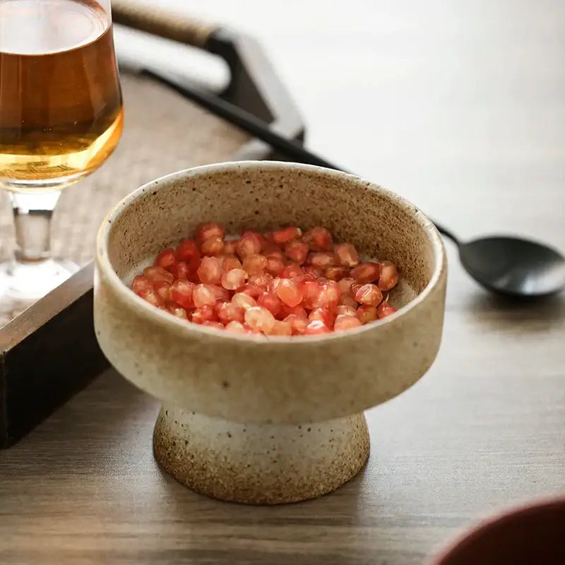 A retro floral ceramic beige and white speckled footed bowl filled with vibrant red pomegranate seeds by decorbites handmade