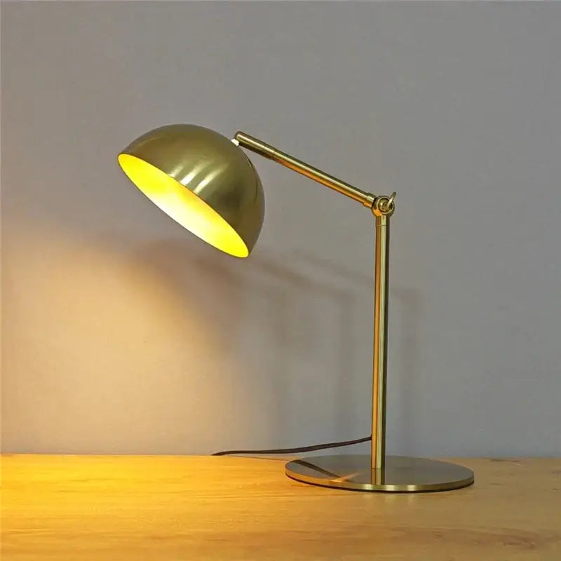 Brass-finished retro gold adjustable angle floor lamp with dome-shaped shade and warm yellow interior glow for reading