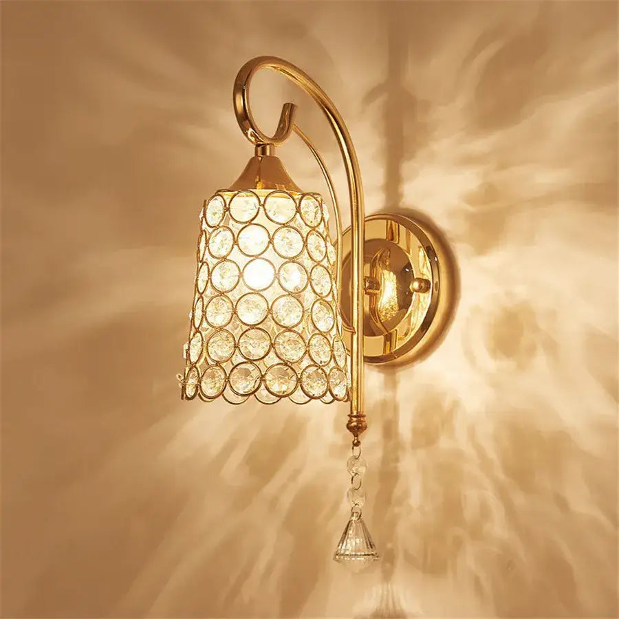 Gold-toned wall sconce with cylindrical crystal shade and dangling pendant for retro gold and chrome crystal wall decorbites light