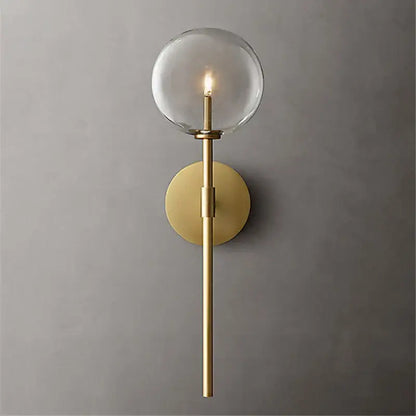 Retro gold wall sconce with a clear glass ball and slender cylindrical stem for living room lighting