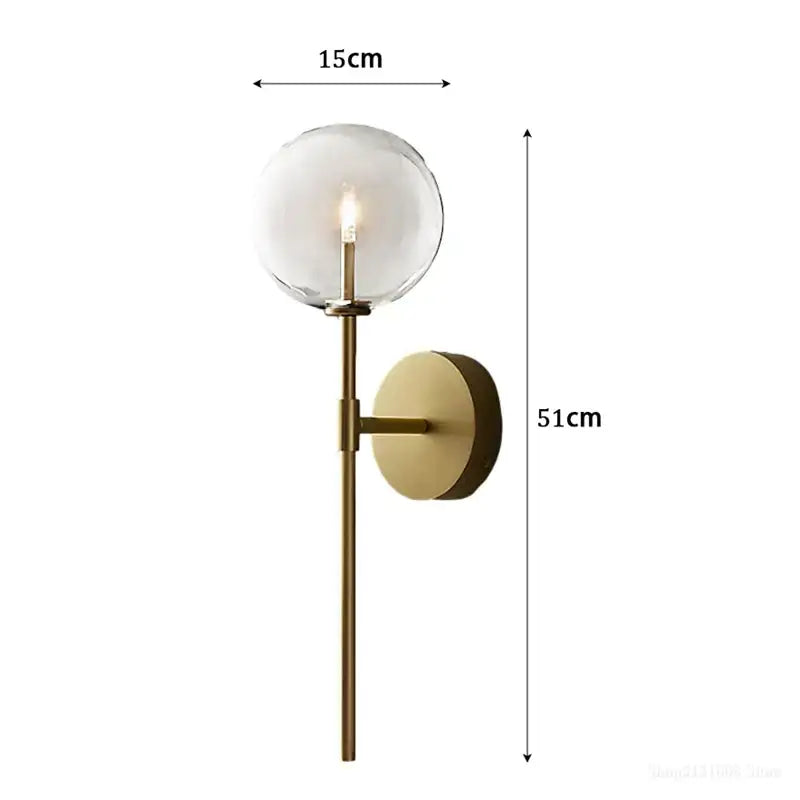 Retro gold wall sconce featuring a clear glass ball globe and slender rod for elegant living room lighting