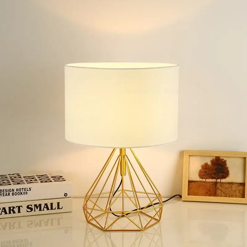 Retro gold geometric table lamp with a gold wire base and white cylindrical shade for study room use