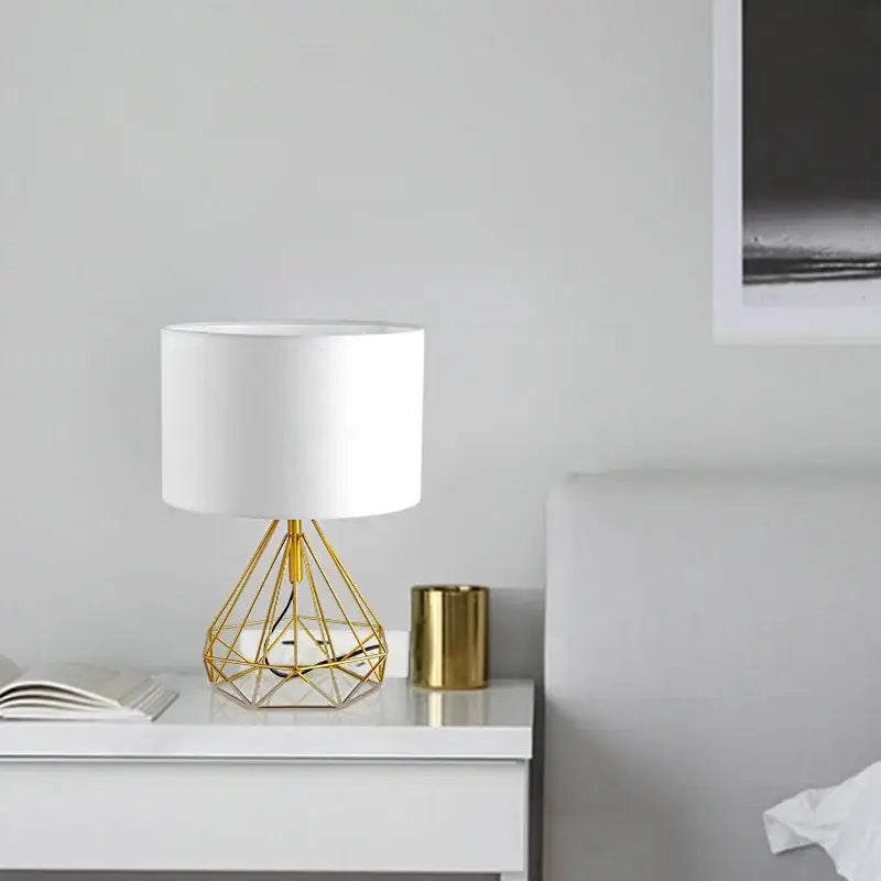Retro gold geometric table lamp with gold wireframe base and white cylindrical shade for study room use
