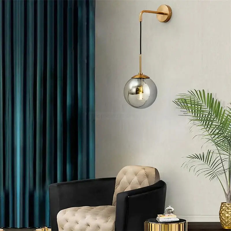 A sleek spherical glass ball wall lamp with gold-toned metal arm for retro decorbites glass ball bedroom sconce lighting