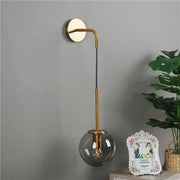 Retro gold glass ball wall lamp with gold-toned curved arm and smoked glass shade for bedroom decorbites glass ball sconce