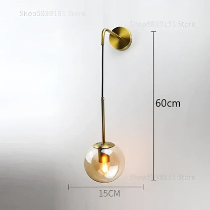Gold-toned wall lamp with decorbites glass ball and slender metal arm for bedroom smoked glass ball wall decor