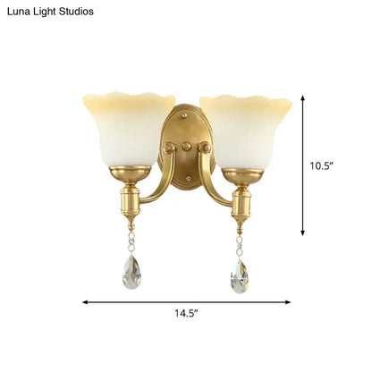 Gold-finished wall lamp with two cream scalloped blossom opaque glass shades and crystal teardrop pendants for bedroom use