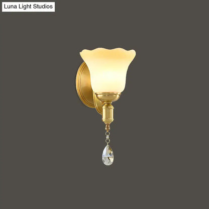 Gold-toned retro wall lamp with blossom opaque glass shade and dangling crystal teardrop for bedroom sconce lighting