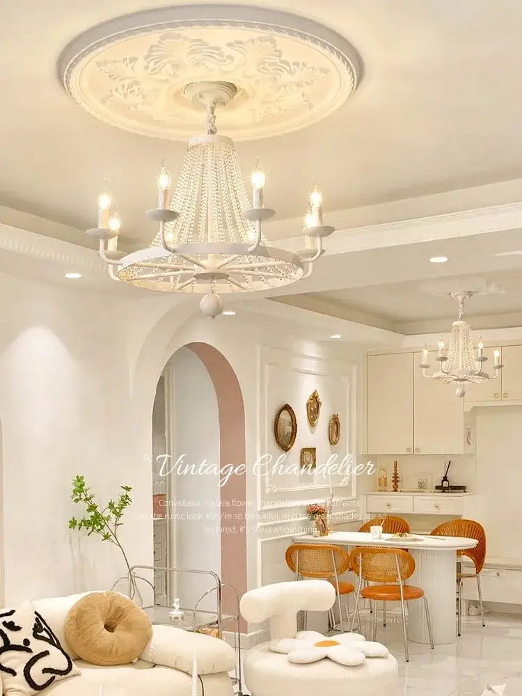 A white ornate decorbites crystal chandelier with beaded crystals and candle-style lights for dining room lighting