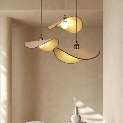 Three cream-colored decorbites hat pendant lights with brass accents and warm glow for dining room decor