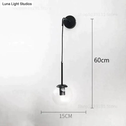 Black metal wall lamp with slender curved arm and clear glass globe bulb for nordic retro modern bedroom lighting