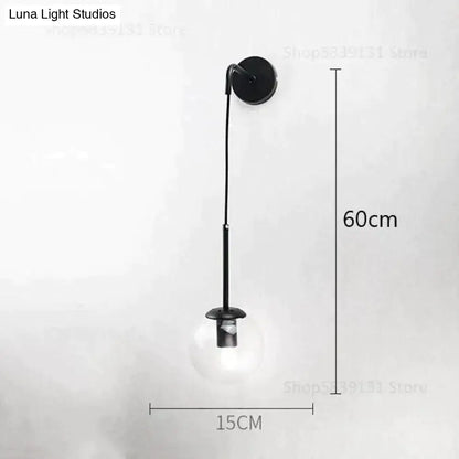 Black metal wall lamp with a slender curved arm and clear glass bulb for retro modern glass bedroom lighting