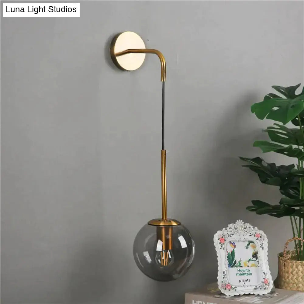 A sleek gold-toned nordic retro modern wall lamp with a curved arm and smoked glass globe for bedroom lighting