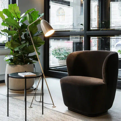 Dark brown velvet armchair with rounded contours next to retro nordic grasshopper floor lamp for stylish living room decorbites grasshopper floor
