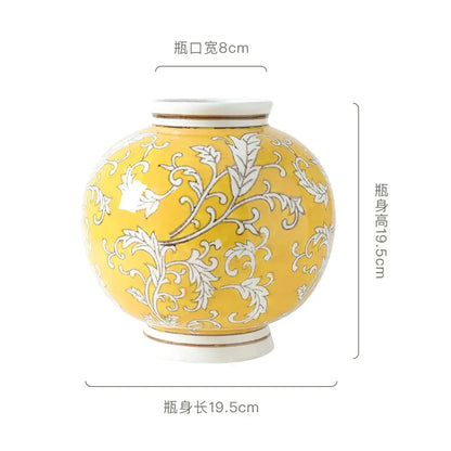 A round glossy yellow ceramic vase with white floral patterns and cream accents for retro living room decorbites blue white style