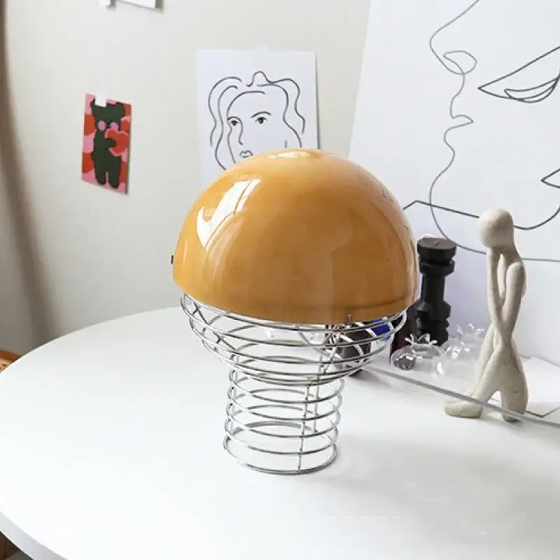 Glossy mustard-yellow dome glass table lamp with a chrome metallic wireframe base for bedroom use