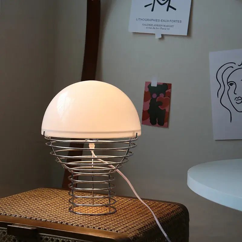 Retro red glass table lamp with a smooth white acrylic shade and chrome wireframe base for bedroom use