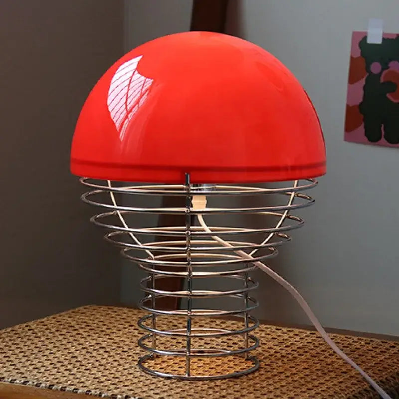 Retro red glass table lamp with vibrant dome-shaped shade and chrome wireframe base for bedroom use