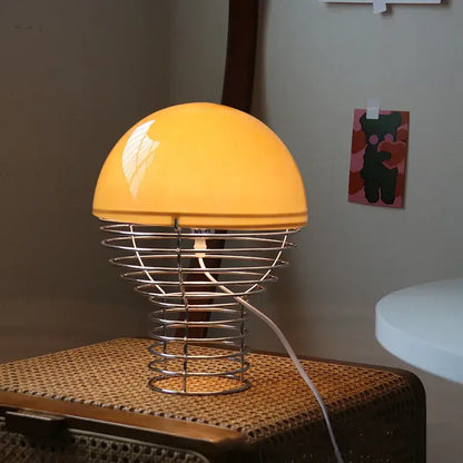 Retro red glass table lamp with warm yellow dome shade and chrome wireframe base for bedroom use
