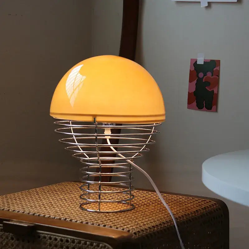 Retro red glass table lamp with warm yellow dome shade and chrome wireframe base for bedroom use