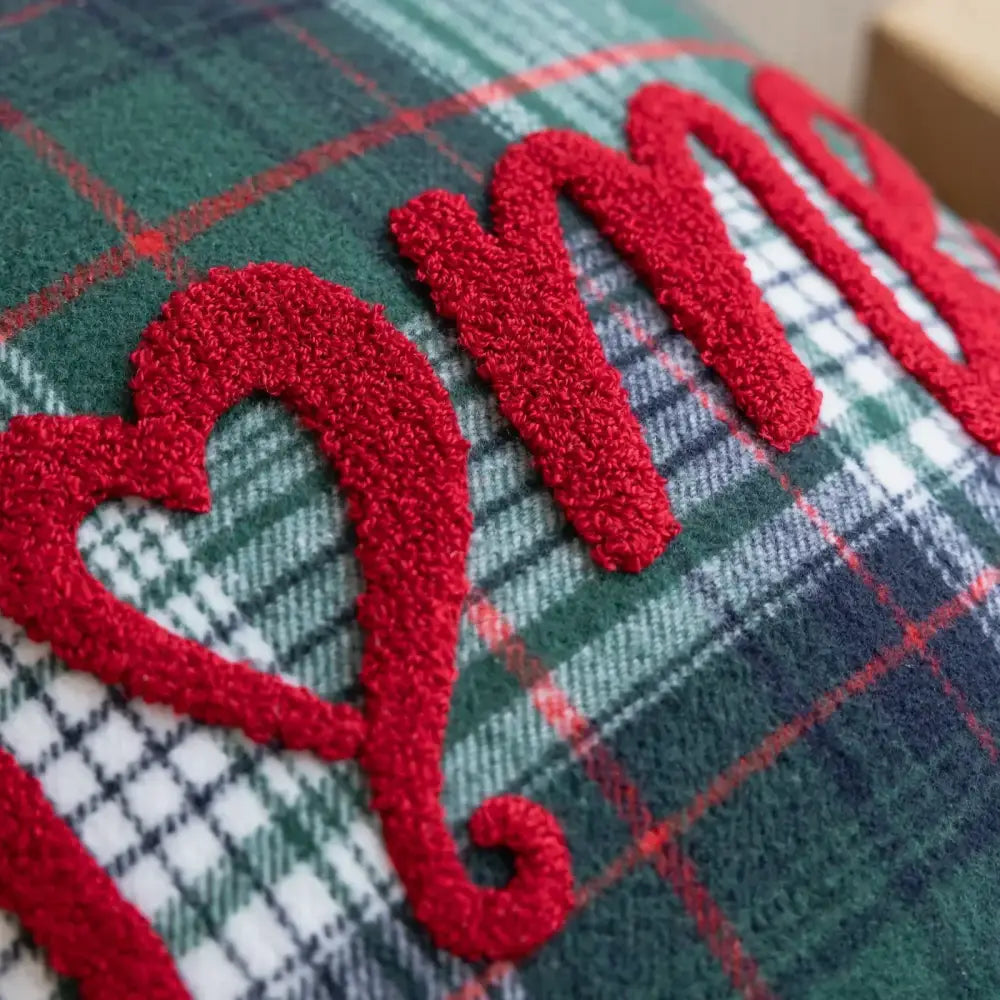 Red embroidered mom appliqué on a green white and red plaid pillow case for snowflake jingle bell decor