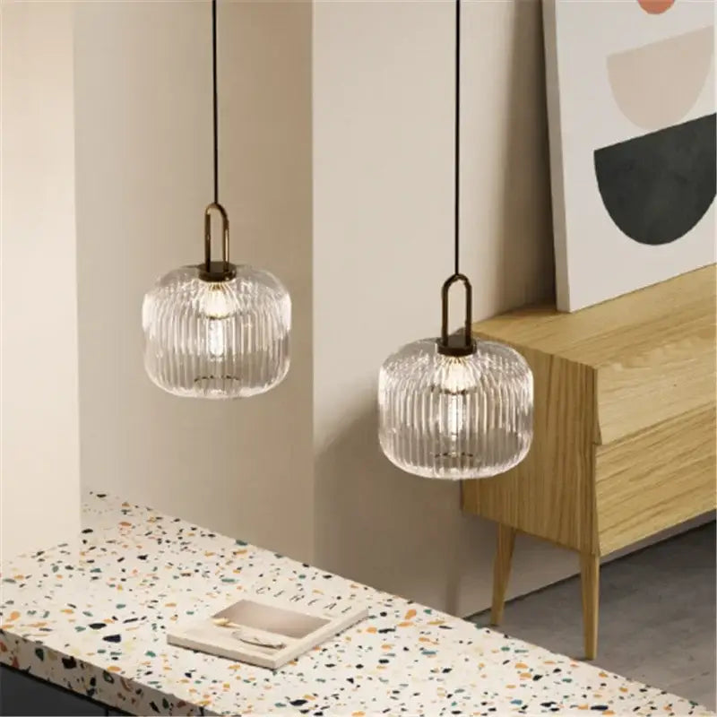 Two clear ribbed glass pendant lights with brass fixtures and black cords for dining room use