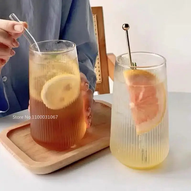 Two clear ribbed glass coffee cups with textured vertical lines and metallic stirrers in a retro design set