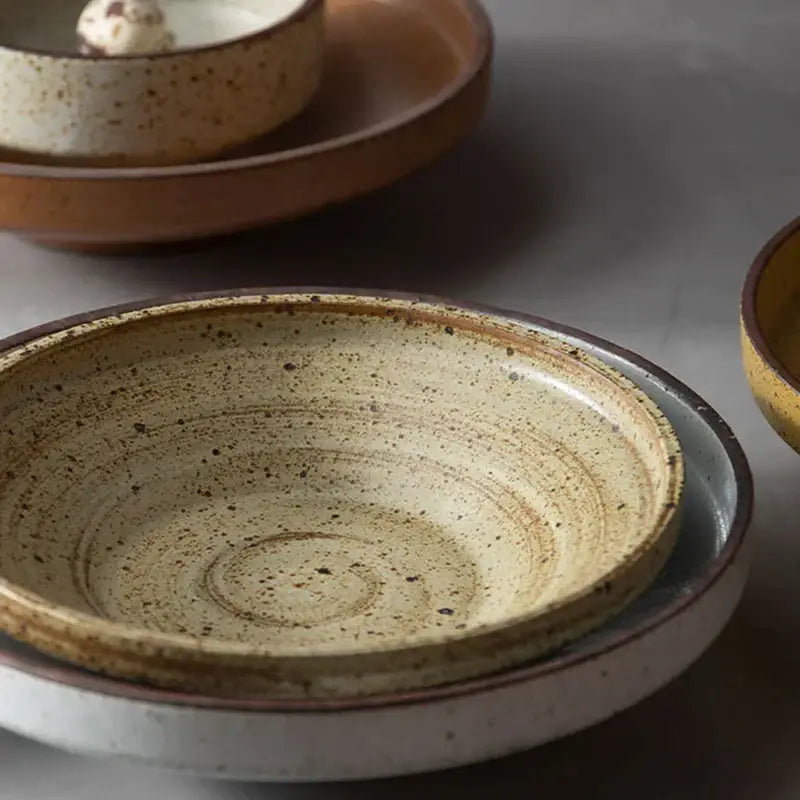Earthenware bowl with speckled beige glaze and subtle ridges on a matching decorbites ceramic round plate set
