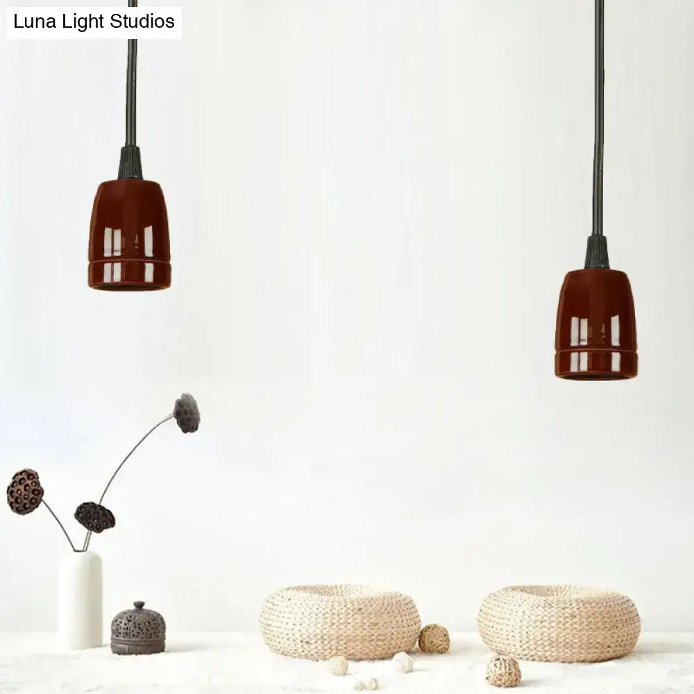 Two decorbites™ retro style pendant lights with glossy black red ceramic shades and adjustable cords hanging from ceiling
