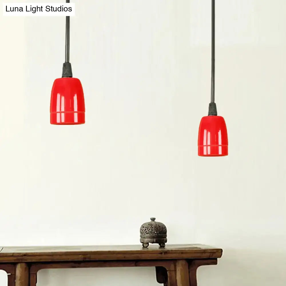 Two vibrant red ceramic ceiling pendant lights with glossy black red ceramic shades and adjustable cords hanging