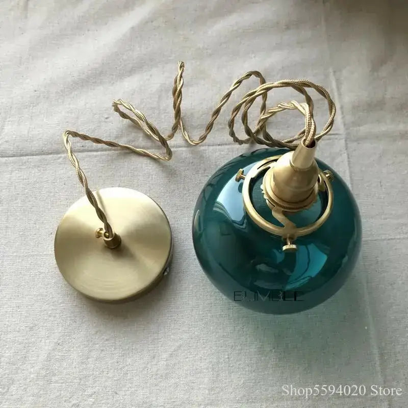 Retro teal and brass glass pendant chandelier featuring a ceramic globe light with brass hardware and twisted cord