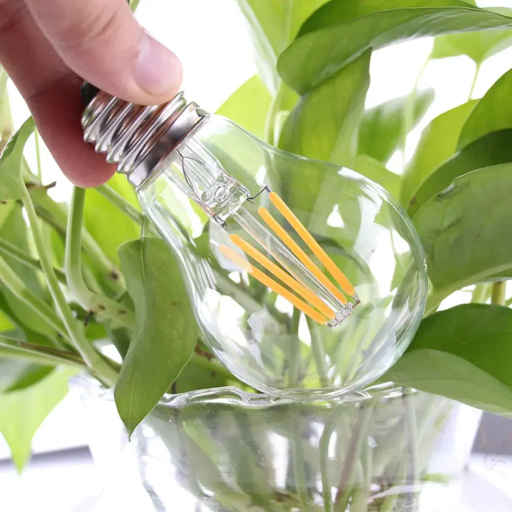 Clear glass edison led bulb with metallic base and warm yellow filament strands for retro living room lighting