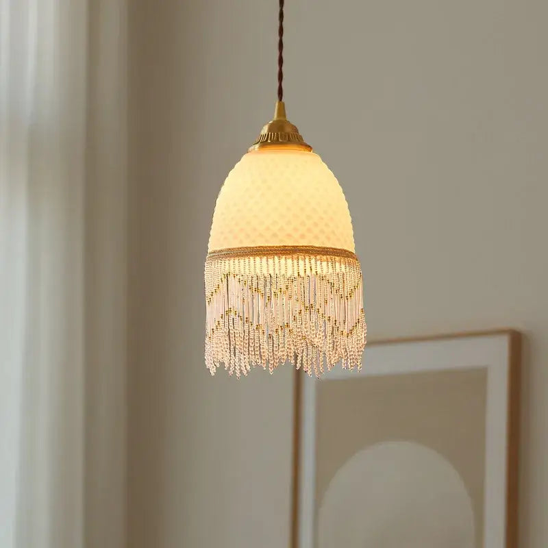 A warm-toned dome pendant light with off-white textured glass and gold-trimmed decorbites glass tassels led design