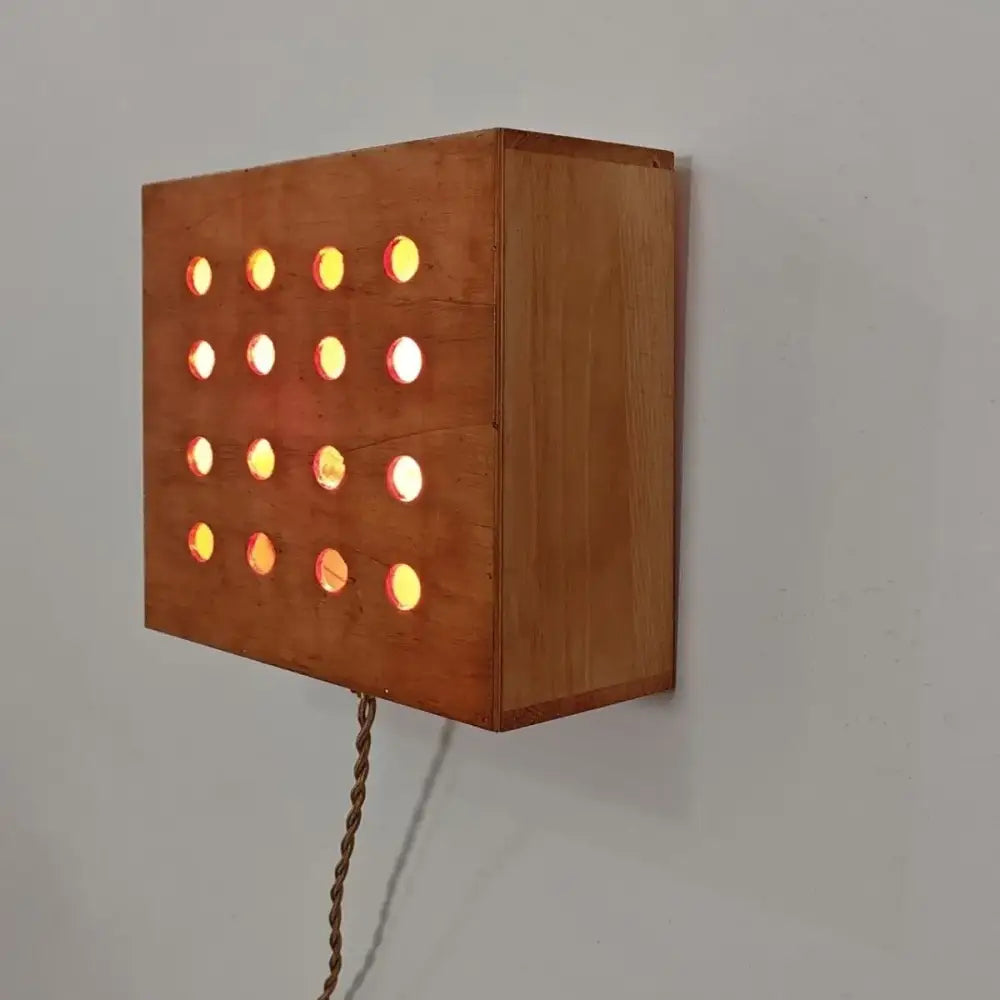 A warm-toned wooden cave box retro wall light with circular cutouts emitting soft amber and white glow for bedroom decorbites
