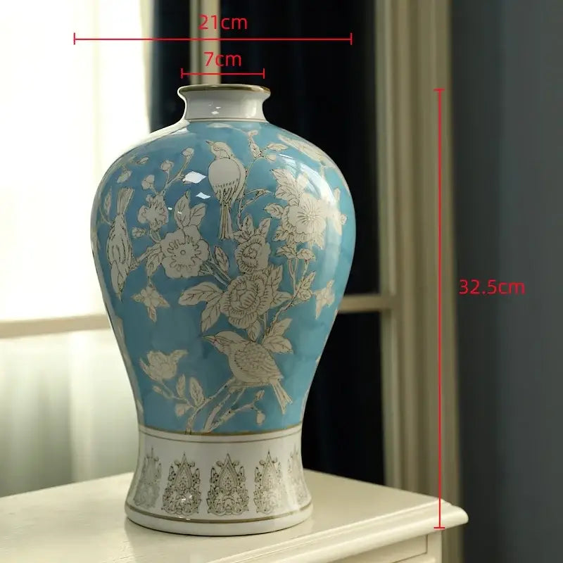 A blue white porcelain vase with intricate gold floral and bird motifs on a decorative base for living room decorbites decor