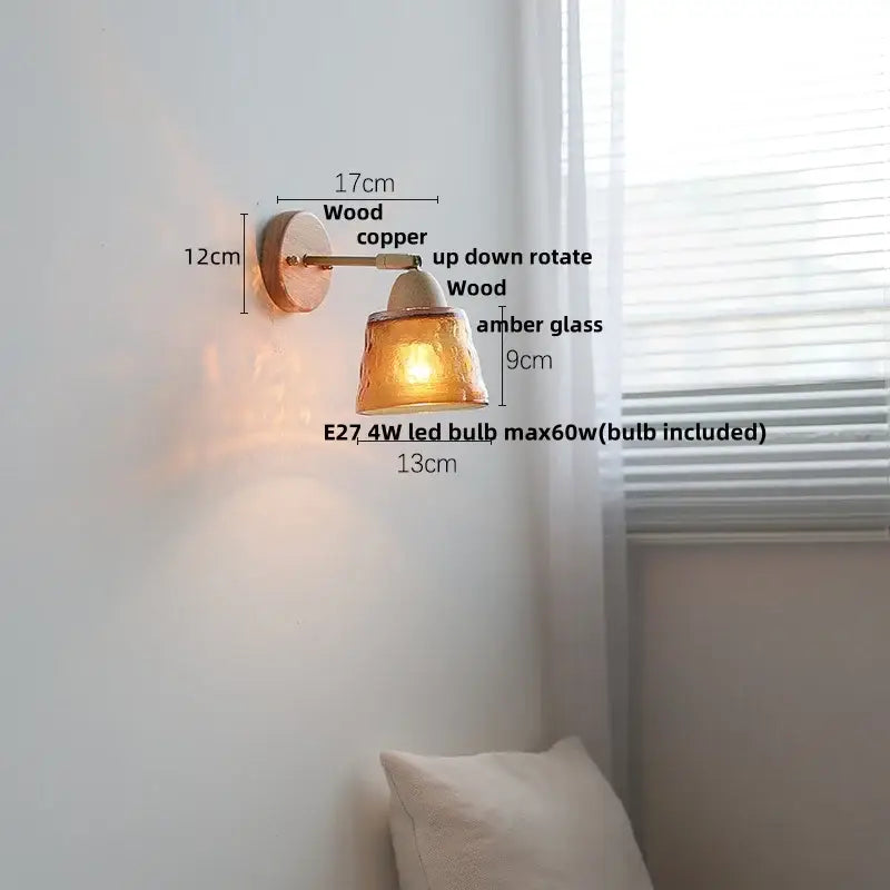 A warm amber glass wall sconce light with wooden and copper fixture designed for adjustable up-down rotation