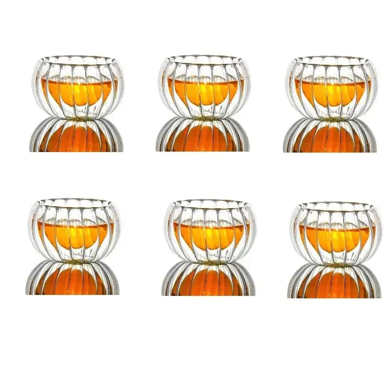 Clear double wall glass teacup set with ribbed pumpkin design containing amber liquid for dining room glassware