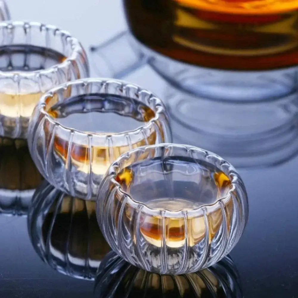 Clear ribbed double wall glass teacup set with fluted design filled with amber liquid for dining room use
