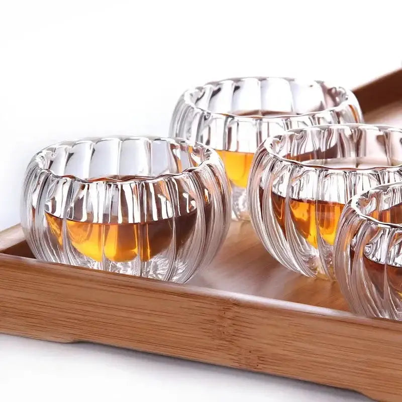 Clear double wall glass teacup set with ribbed design holding golden amber liquid for elegant dining room use